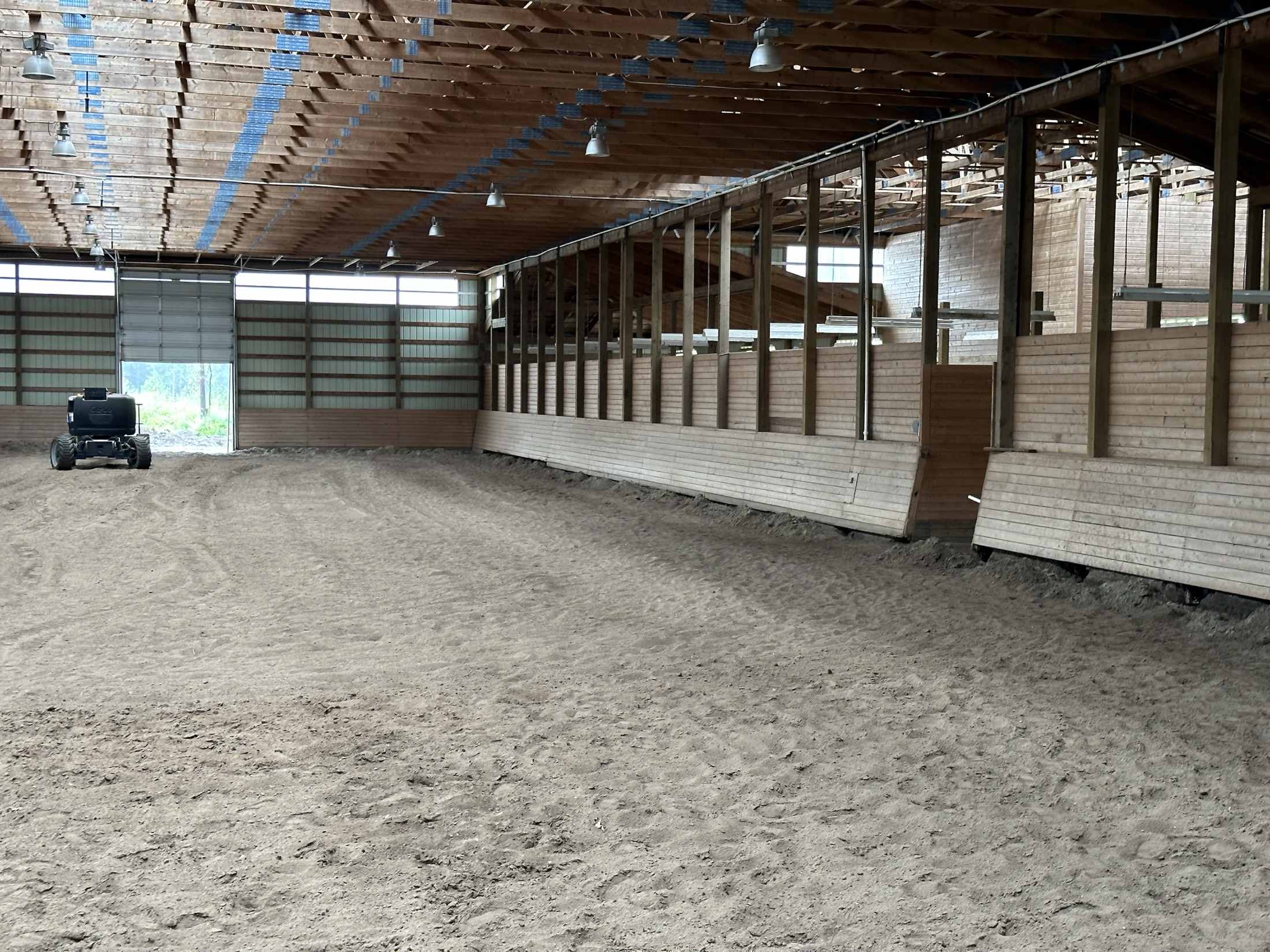 Coast Performance Horses arena interior mid-install — finished kick wall on one side, bare framing on the other, Langley