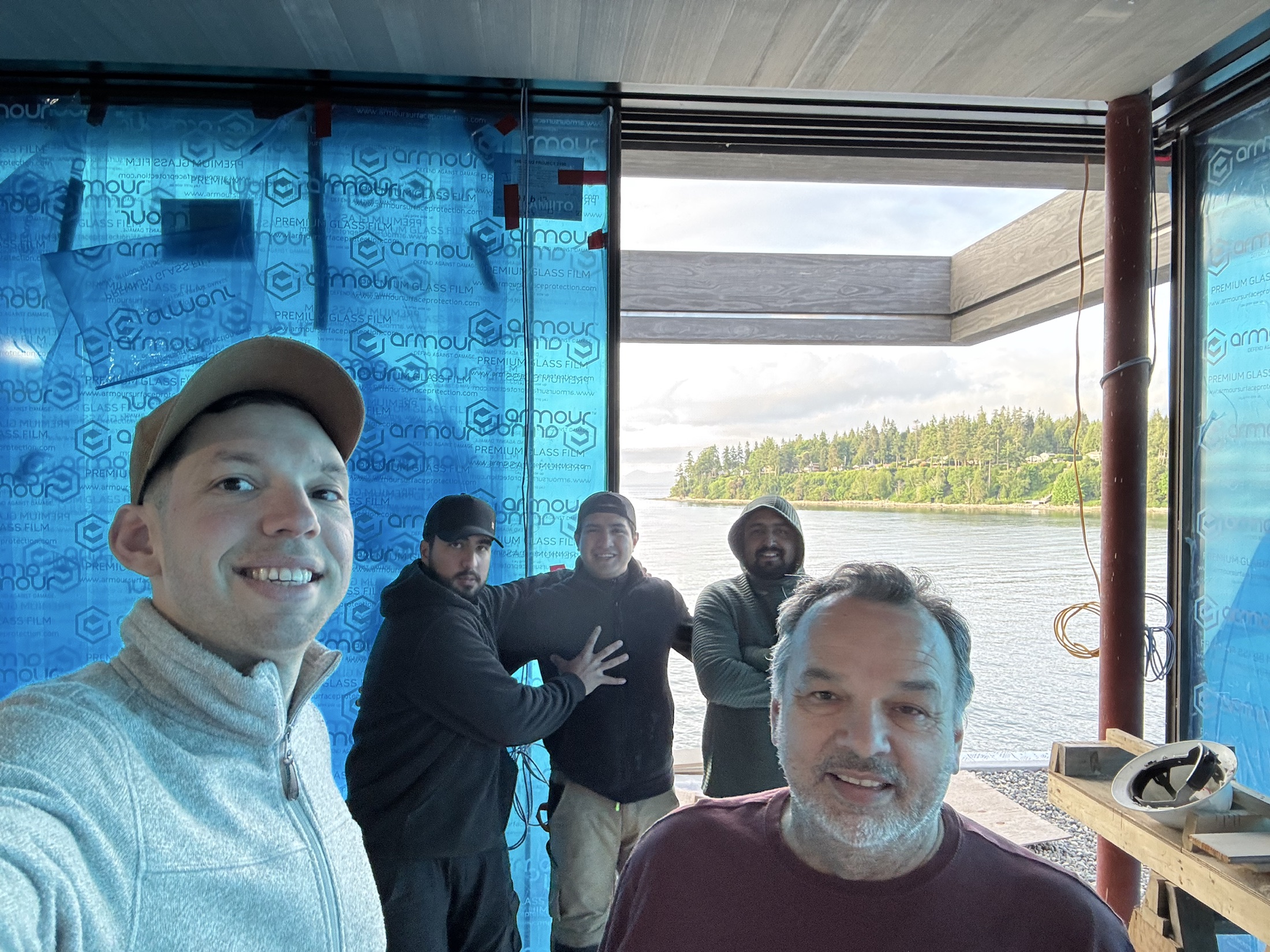 The Renova Design Build crew together on-site at the Cove Beach custom home in Sechelt, the ocean behind them