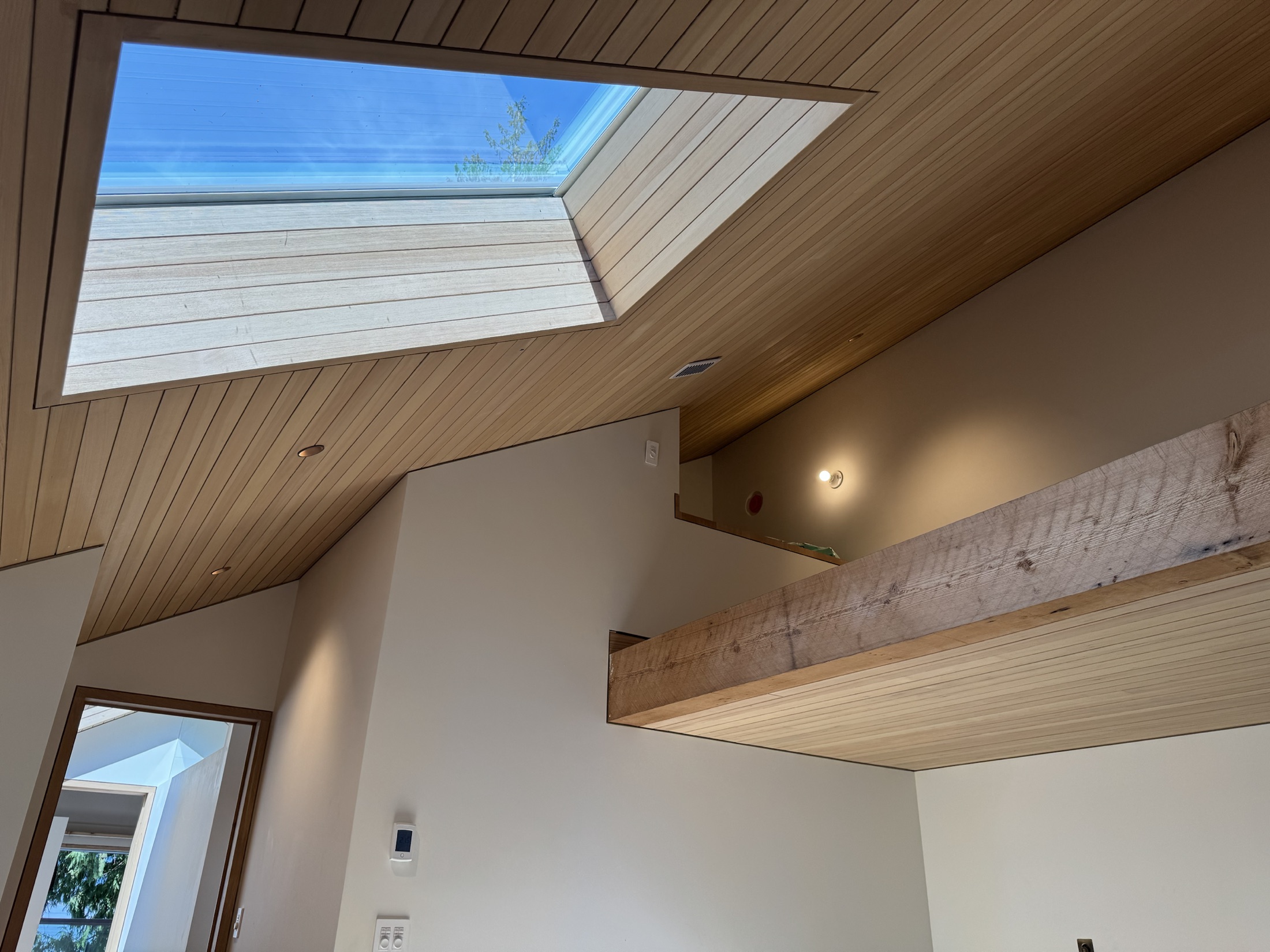 Hemlock ceiling wrapping into a skylight well with an exposed timber beam at the Lawrence Way custom home, West Vancouver