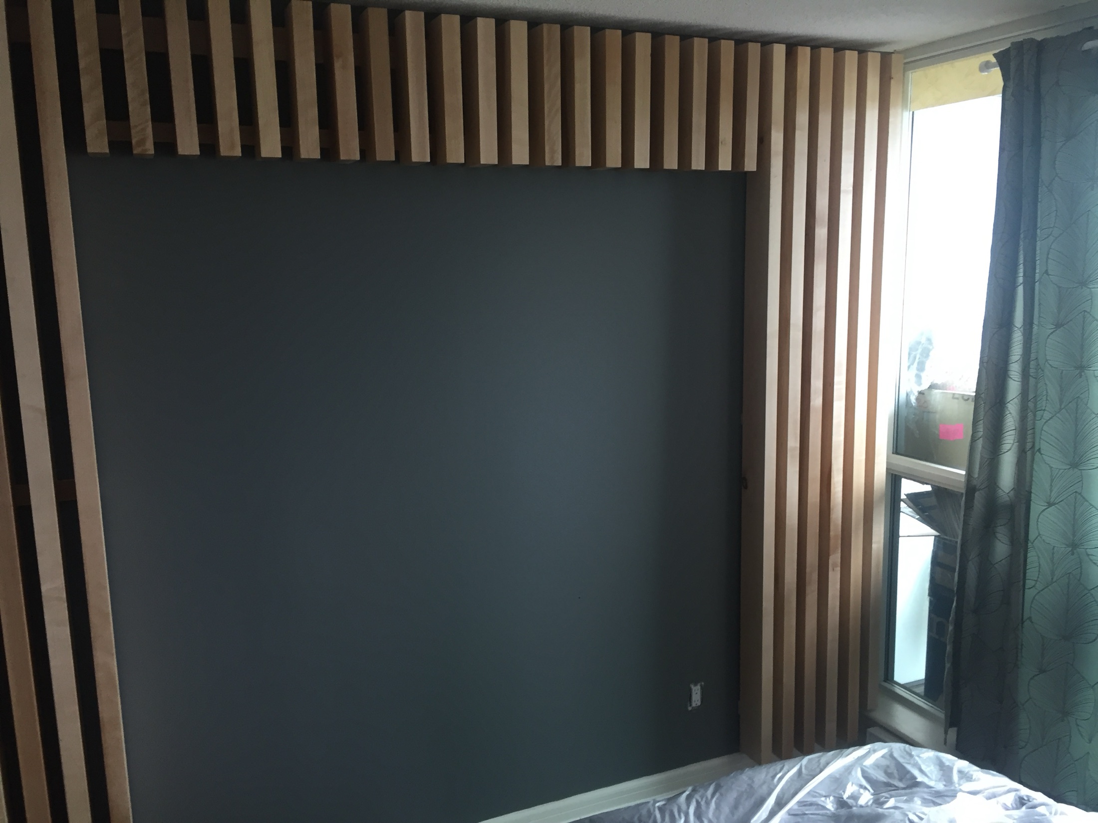 Custom slat-wall millwork — vertical wood battens over a dark feature wall, wrapping onto the ceiling