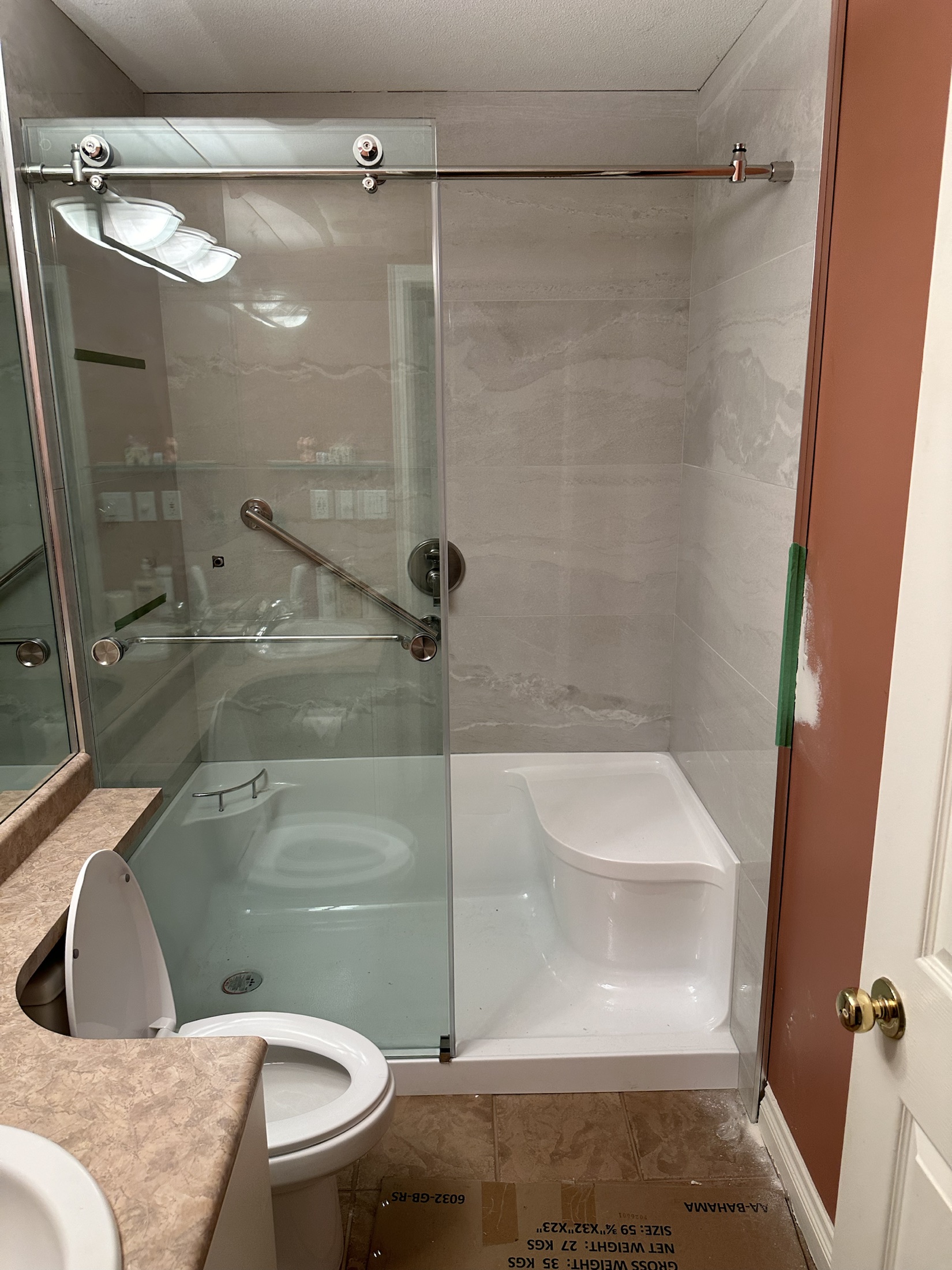 Paula Dhillon bathroom renovation in Surrey, mid-renovation — new shower set, walls taped and unpainted, dated vanity and toilet still in place