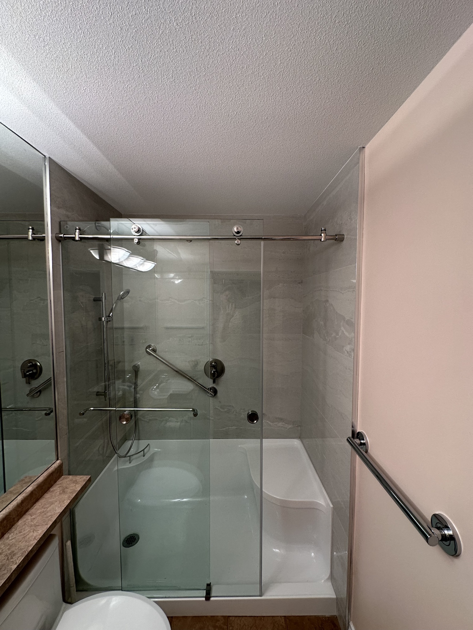 Finished Paula Dhillon bathroom in Surrey, wider view of the frameless glass shower and bench
