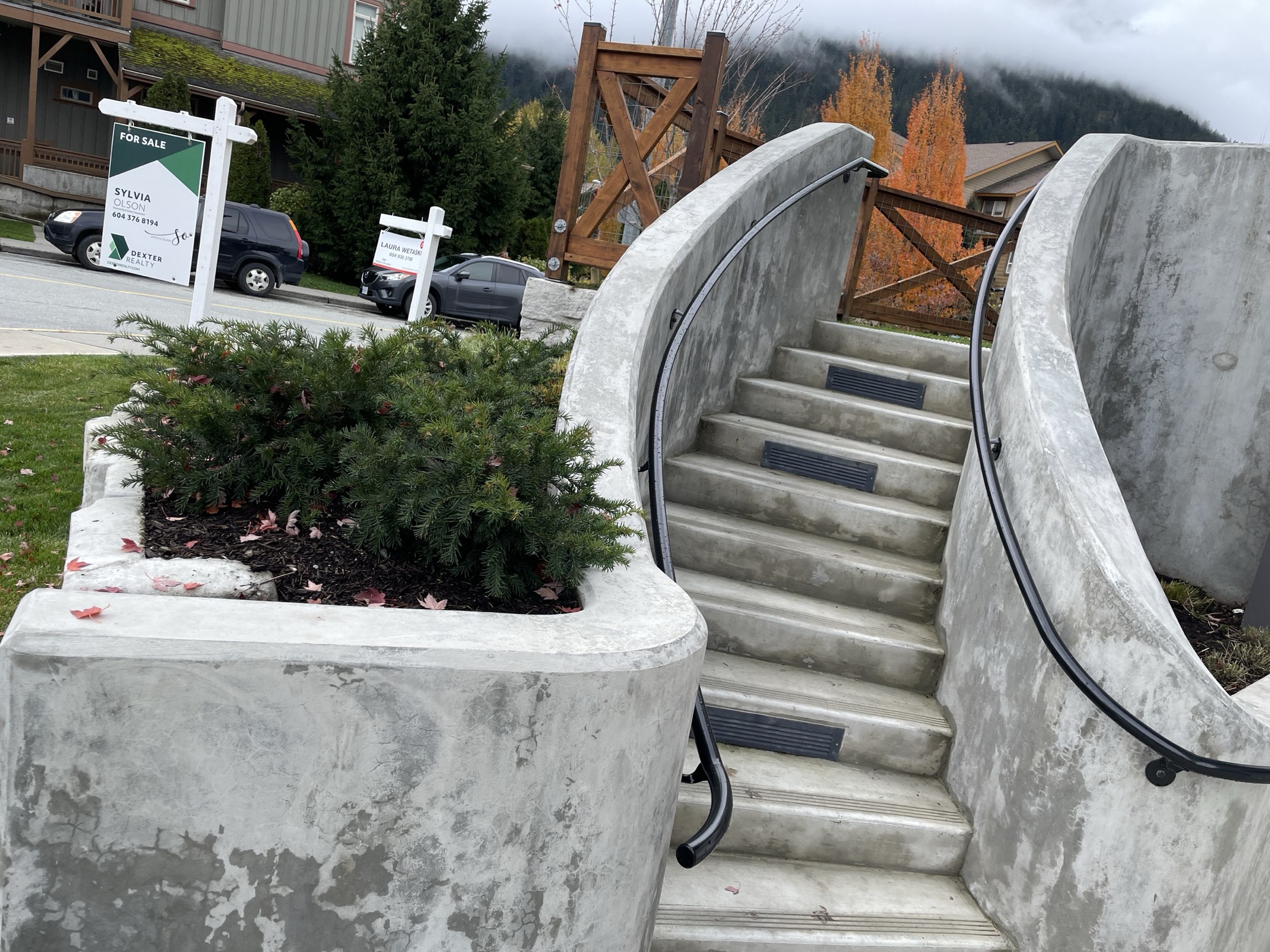 Finished curved cast-in-place concrete staircase on a Pemberton townhouse development, both curved walls with a mountain backdrop, general contractor Maple Reinders